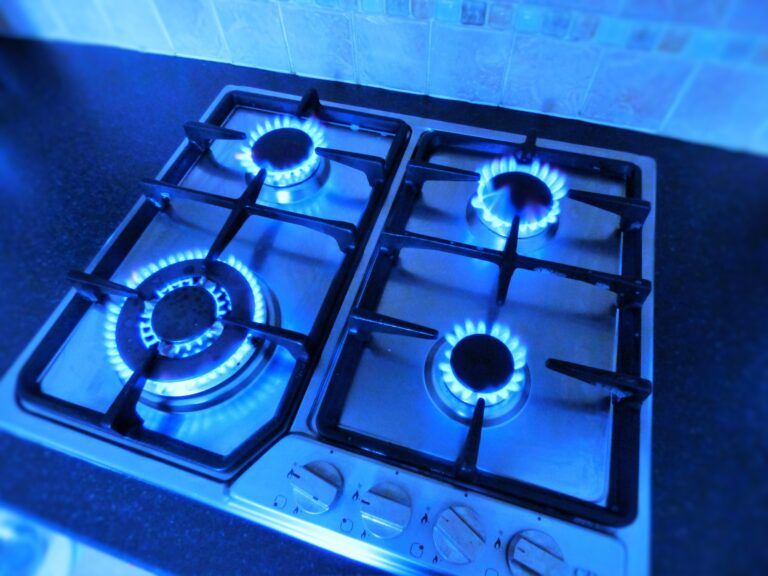 GAS COOKER STOVE / HOB: LIT GAS FLAMES, FOUR BURNERS WITH BLUE LIGHTING. TOP VIEW.