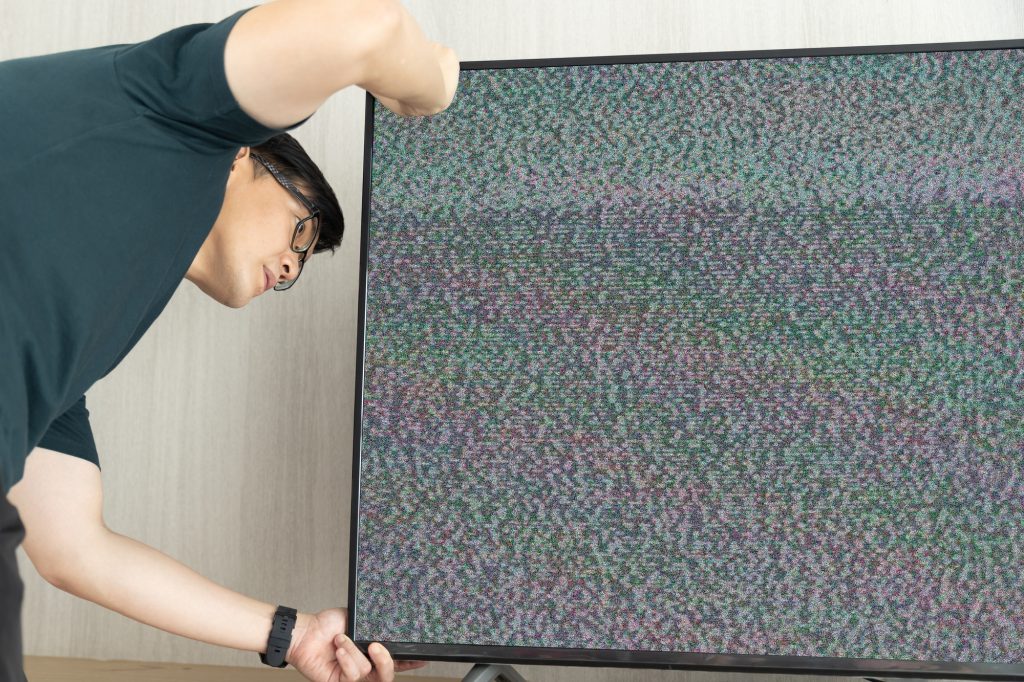 a man fix television lost signal noise on screen looking cable behide