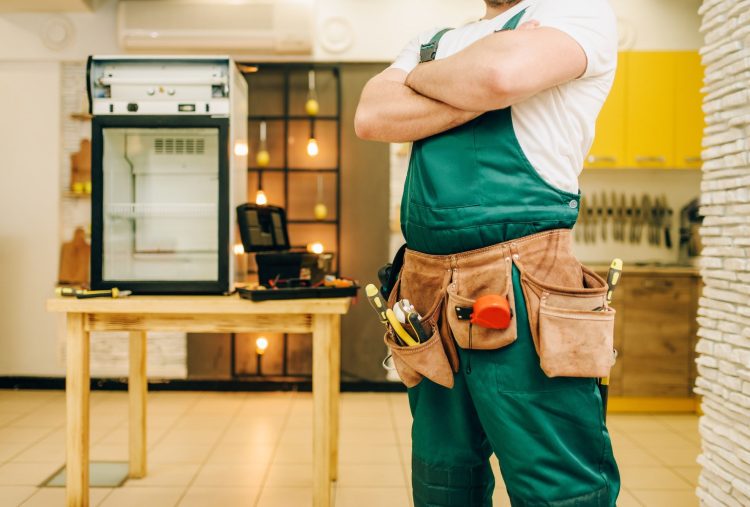 Worker in uniform against refrigerator on table